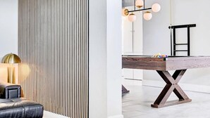 A modern room with a pool table, a sofa, and a decorative wall panel. - Luxury 4BR 2BA House with Pool Spa Billiard Only 6 minutes to the Strip (Las Vegas)