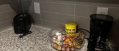 A kitchen counter with a toaster, a coffee maker, and a container of coffee pods.