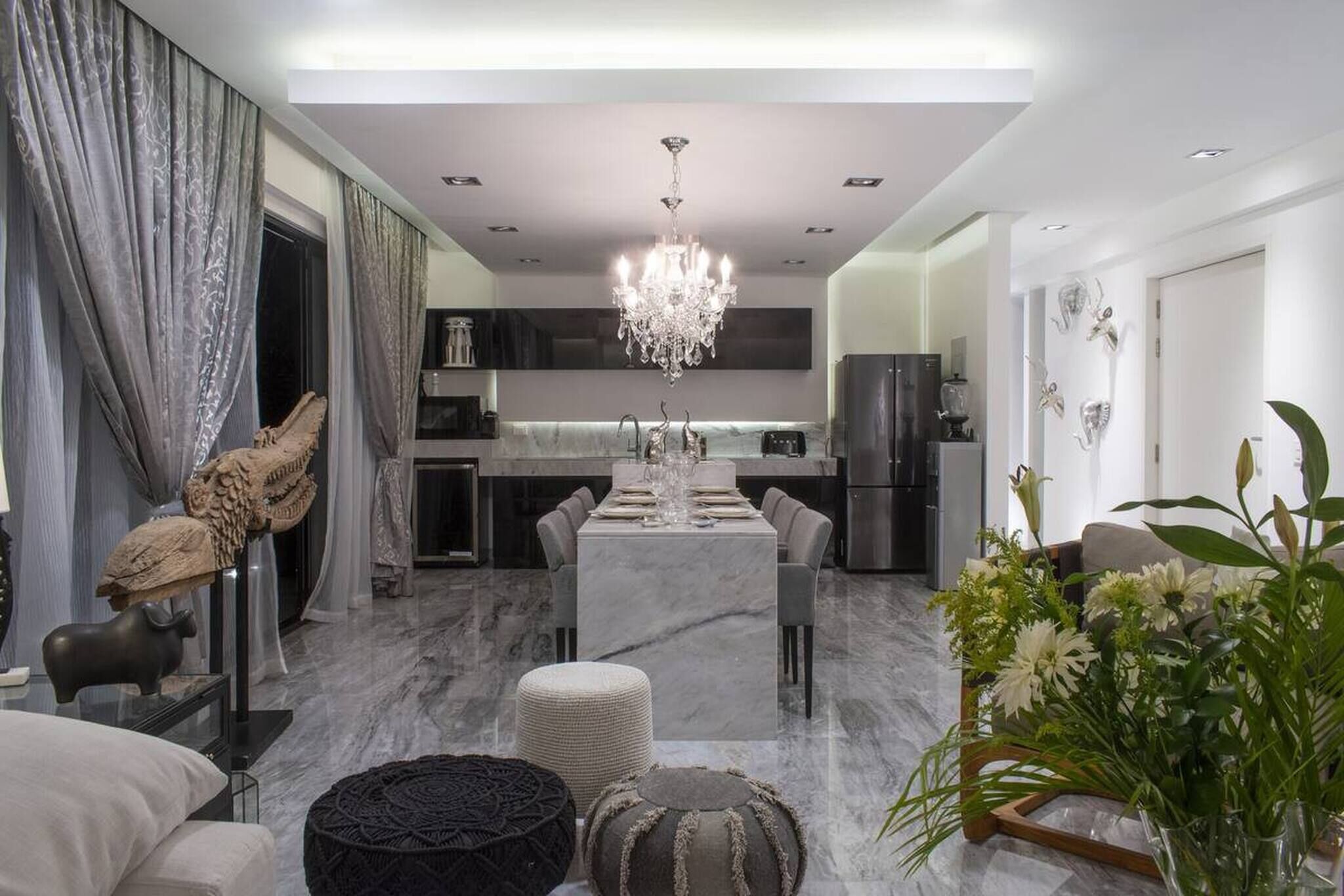 A modern kitchen with a central island, a chandelier, and a dining area with a table set for four.