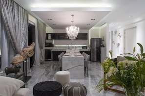 Una cocina moderna con una isla central, una araña y un comedor con mesa para cuatro.