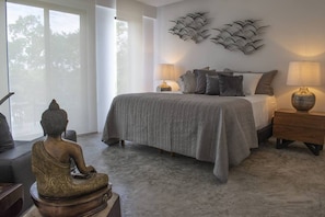 A bedroom with a bed, bedside lamps, a Buddha statue, and a wall art piece. - Bh 08 - Penthouse Ganesh And The Dragon (Tulum)