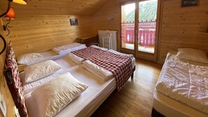 A cozy cabin room with two beds, a wooden ceiling, and a window with a view of trees. - Chalet Le Castor: in the center of Chatel (Châtel)