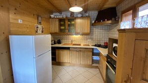 A kitchen with wooden cabinets, a white refrigerator, a sink, and a stove. - Chalet Le Castor: in the center of Chatel (Châtel)
