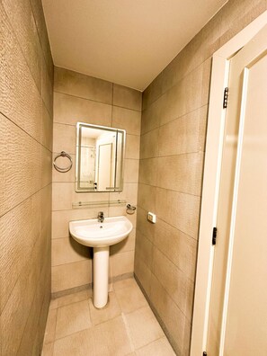 A bathroom with a white sink, a mirror, and a towel ring on the wall.