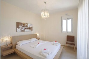 A hotel room with a bed, bedside lamps, a chair, a window, and a painting on the wall.