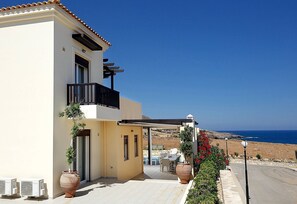 A residential building with a balcony, a covered patio, and a view of the sea.
