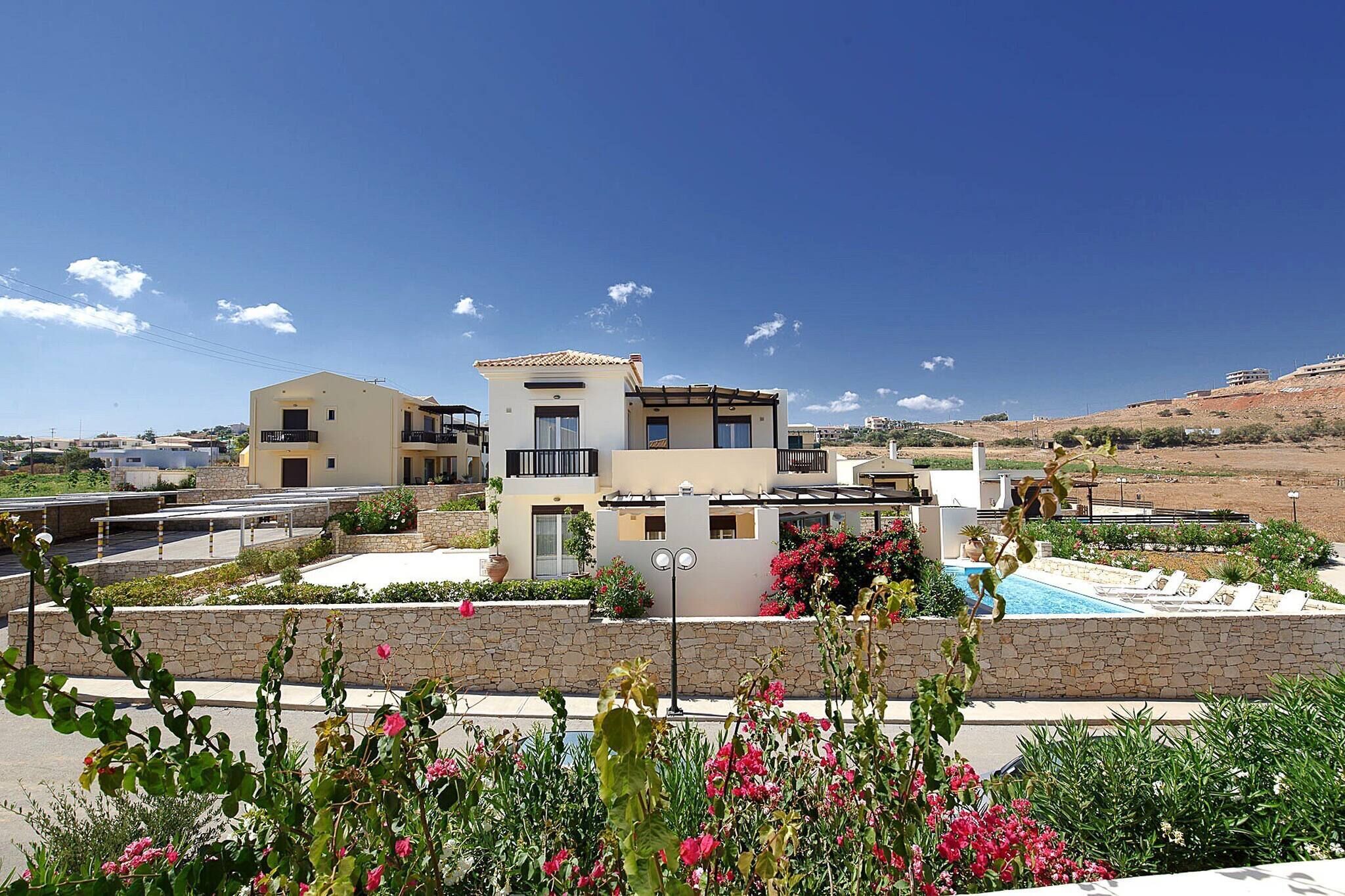 Una casa moderna de dos pisos con piscina, rodeada de un jardín ajardinado y un cielo azul despejado.