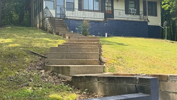 A single-story house with a front porch, a staircase leading to the entrance, and a small front yard.