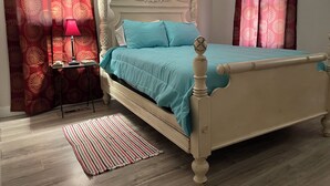 A neatly arranged bedroom with a bed, a bedside table, a lamp, and a rug.