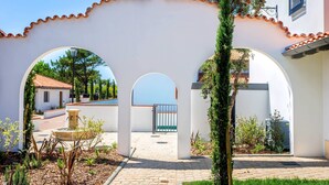 A courtyard with white walls, a tiled roof, and a fountain.