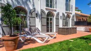 A modern building with arched windows and a patio area with lounge chairs and a table.