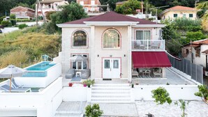 Une maison à deux étages avec une piscine, un balcon et un auvent rouge.
