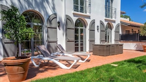 Un bâtiment moderne doté de fenêtres en arc de cercle et d’un patio aménagé avec des fauteuils et une table.