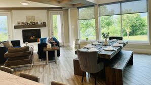 A spacious living room with a fireplace, large windows, and a dining area. - Eagles' View Retreat! Family-sized home in Texas countryside with stunning views (Gordon)