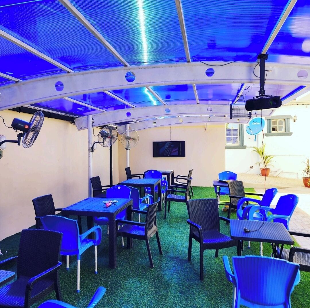 An indoor dining area with tables and chairs, ceiling fans, and a projector.