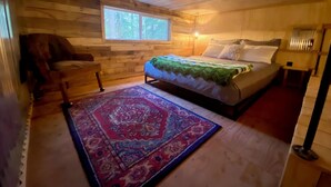 Un dormitorio acogedor con cama, una silla, una ventana y una alfombra.