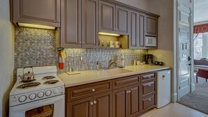 A kitchen with brown cabinets, a white stove, and a microwave. - Dog Friendly- Downtown - Historic Palace Hotel Condos- Suite 202 (Salida)