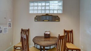 A dining area with a round wooden table, four wooden chairs, a window with frosted glass, and a mirror above the table. - Dog Friendly- Downtown - Historic Palace Hotel Condos- Suite 202 (Salida)