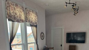 Una sala de estar con un sofá, una mesa de comedor con sillas, un televisor y un radiador.