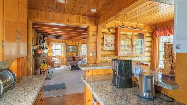 L’intérieur d’une cabane en rondins comprend une cuisine, un coin repas et un salon.
