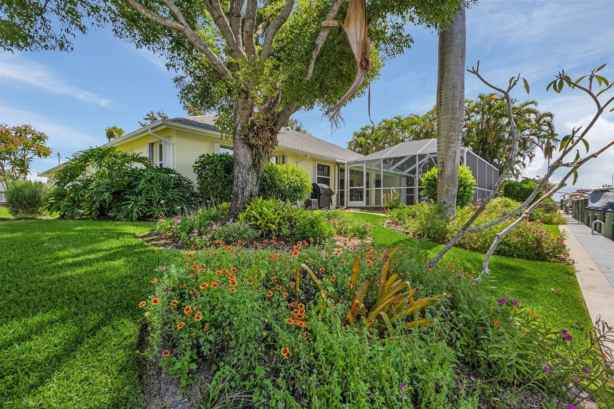 A yellow house with a covered porch, surrounded by a well-maintained garden with various plants and flowers.