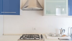 A kitchen with a gas stove, a coffee maker, and a window with a view. - Elegant Residence Ea Bianca 4 Bedroom Apartment Sleeps 8 Extra bed Available (Arzachena)