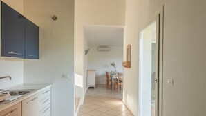 A modern kitchen with a sink, cabinets, and a dining area with a table and chairs. - Elegant Residence Ea Bianca 4 Bedroom Apartment Sleeps 8 Extra bed Available (Arzachena)