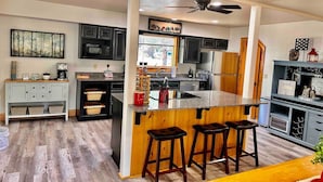 A modern kitchen with a central island, bar stools, and a ceiling fan. - Timber Terrace - .9 mi Downtown *pet friendly (Prescott)