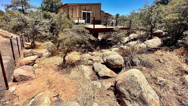 A rustic cabin with a wooden exterior, surrounded by a rocky landscape and sparse vegetation. - Timber Terrace - .9 mi Downtown *pet friendly (Prescott)