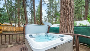 A hot tub on a wooden deck surrounded by trees.