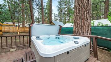 A hot tub on a wooden deck surrounded by trees.