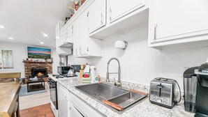 A modern kitchen with white cabinets, a granite countertop, a stainless steel sink, a toaster, and a coffee maker.
