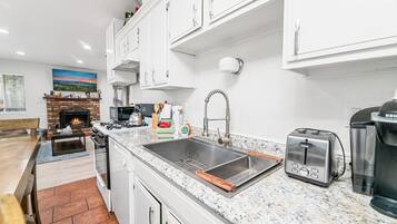 A modern kitchen with white cabinets, a granite countertop, a stainless steel sink, a toaster, and a coffee maker.