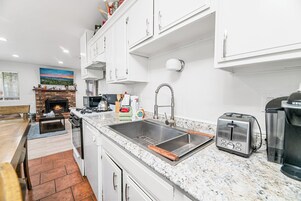 A modern kitchen with white cabinets, a granite countertop, a stainless steel sink, a toaster, and a coffee maker.