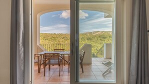 A balcony with a table and chairs, a view of a hilly landscape, and a clear sky. - Elegant Residence Ea Bianca 2 Bedroom Sleeps 6 Plus Extra bed Available (Arzachena)