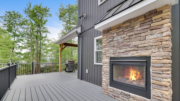 A deck with a stone fireplace, a grill, and a pergola. - Lucky Buck by PMR, 7BR Luxury Cabin, Lake View, EV Charge, Sleeps 22 (Lake Harmony)