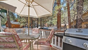 An outdoor patio with a grill, chairs, and a table under a canopy. - Oak Nesting (Big Bear Lake)