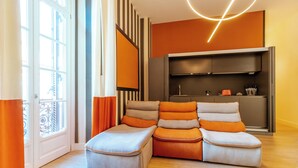 A modern living room with a sectional sofa, a built-in entertainment unit, and a large window with curtains. - Nana Inn Palazzo Nana' (Naples)