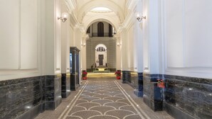 A grand hallway with marble flooring, white walls, and a reception desk at the end. - Nana Inn Palazzo Nana' (Naples)