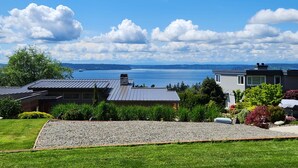 Un quartier résidentiel avec des maisons, une pelouse verdoyante et une vue sur une vaste étendue d’eau.