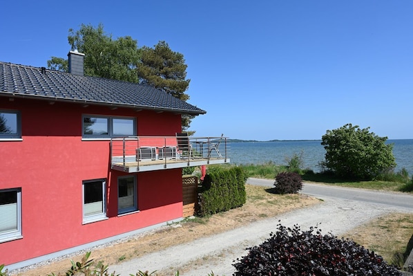 A red two-story house with a balcony overlooking a lake.