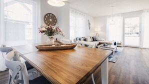 Un salón amplio con una mesa de comedor de madera, un conjunto de sofás y un gran reloj de pared.