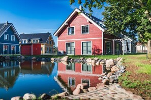 A row of colorful houses with a calm pond in the foreground.