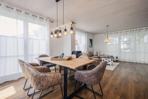 Uma sala de estar espaçosa com uma mesa de jantar de madeira, cadeiras de couro e um sofá.