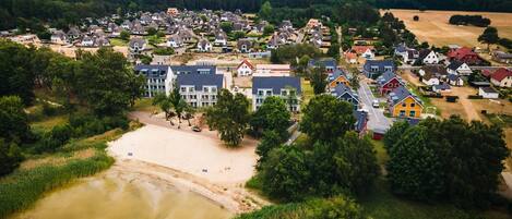 An aerial view of a residential area with houses, a beach, and a river.