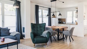 Un salon moderne avec un fauteuil vert, un canapé gris et une table à manger en bois.