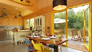 A wooden interior with a dining area, kitchen, and large windows.