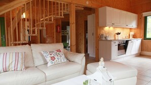 L’intérieur d’un chalet en bois chaleureux et accueillant, avec un canapé, une petite table et un coin cuisine.