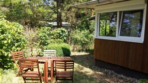 A wooden table and chairs set outdoors with a view of a house and surrounding greenery. - Gemütliches, 30 qm Großes Ferienhaus für 4 Personen. - Minna-busch-weg (Loddin)