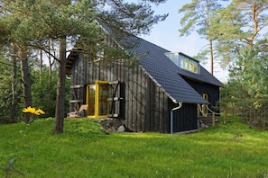 A rustic wooden cabin with a sloped roof, a front porch, and a stone foundation.